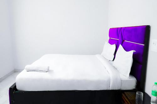 a bedroom with a white bed with a purple headboard at Hotel Inn sky in New Delhi