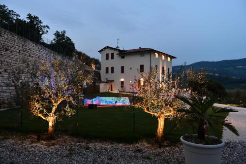 a house with trees in front of a fence with lights at Villa Allegri Agriturismo di Charme in Negrar