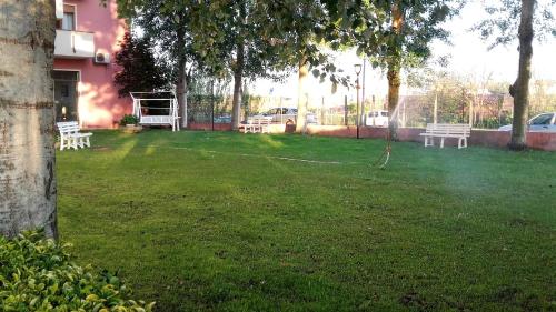a yard with two white benches in the grass at Hotel Europeo in Sottomarina