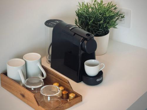 a coffee maker and cups on a counter at Mameli View Cagliari in Cagliari