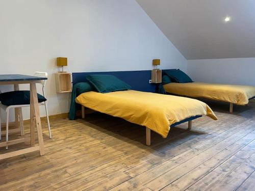 two beds in a room with a desk and a table at Logement en bord de Meuse « La Jolie Rose » in Haybes