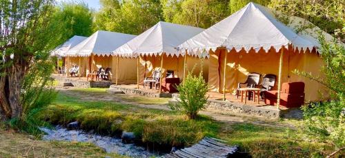 a group of tents with chairs and a river at Royal Deluxe Camp & Resort, Hunder- Nubra in Nubra
