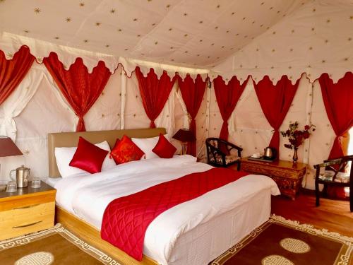 a bedroom with a large bed with red pillows at Royal Deluxe Camp & Resort, Hunder- Nubra in Nubra