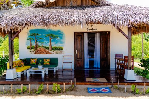 a house with a thatched roof and a patio at Long Beach Resort, Nosy Be in Nosy Be