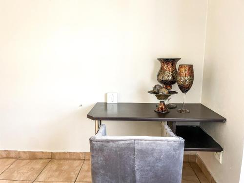 a table with vases and wine glasses on it at Bobisemo Luxury Pretoria East Apartment in Tierpoort