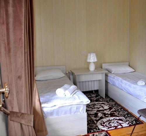 a room with two beds and a table with a lamp at Bilol Guest House in Samarkand