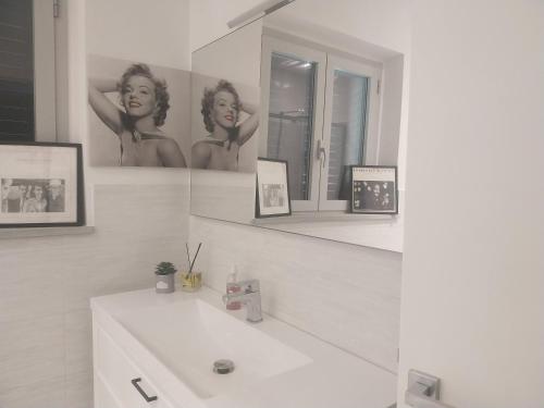 a white bathroom with a sink and a mirror at La casa di Tommy in Cortona