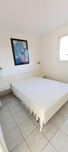 un lit blanc dans une chambre avec une télévision au mur dans l'établissement 3 pièces proche plage commerces et golf, à Pornic