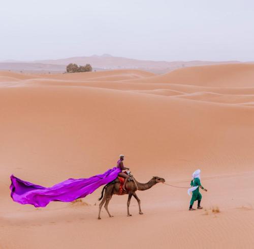 a man on a camel walking in the desert at Luxury Bedouin Camp in Merzouga
