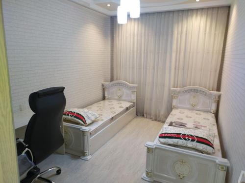 Habitación con 2 camas y una silla. en Апартамент в элитном районе, en Andiján