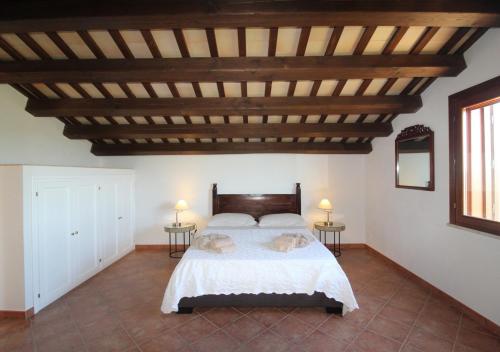 1 dormitorio con cama con sábanas blancas y techo de madera en Villa Colli Ericini, en Baglio Rizzo