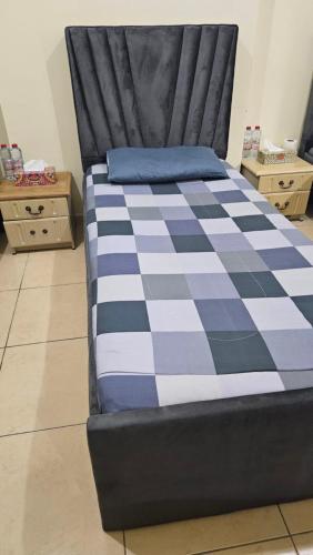 a bed with a blue and white checkered blanket at Paradiso Backpackers Nest 2 in Abu Dhabi