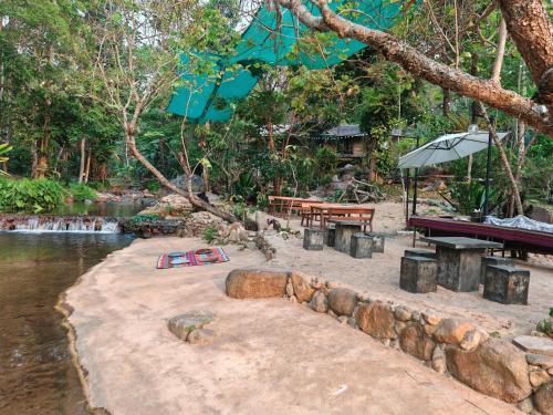 a picnic table and benches next to a river at ธารทอง ลอดจ์ Tharnthong Lodge in Ban Pang Champi
