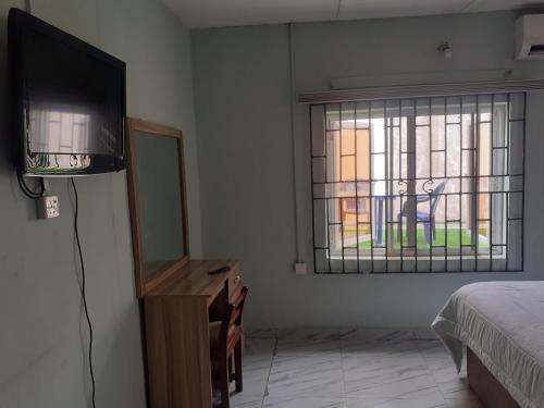 Schlafzimmer mit einem Bett, einem TV und einem Fenster in der Unterkunft Biddex Lodge & Hotels in Benin-Stadt