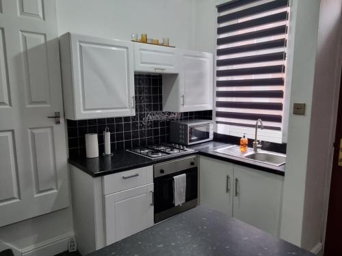 a kitchen with white cabinets and a stove top oven at Be our Guest! Stylish-Central location-Comfy-Cosy in Headingley