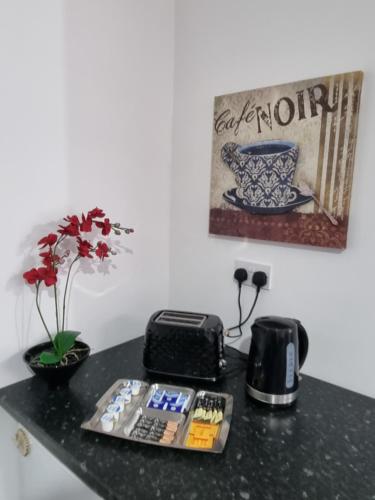 a black counter with a toaster a toaster and flowers at Be our Guest! Stylish-Central location-Comfy-Cosy in Headingley