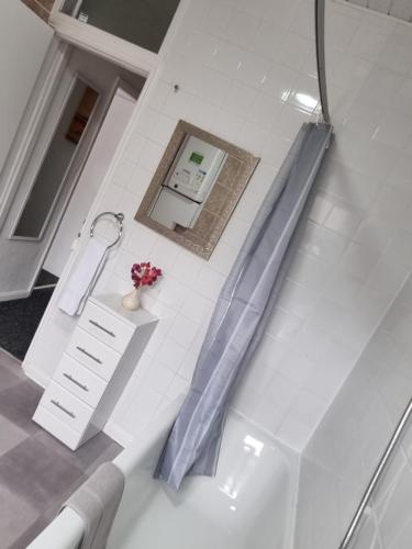 a bath tub with a blue shower curtain in a bathroom at Be our Guest! Stylish-Free parking-Central location in Headingley