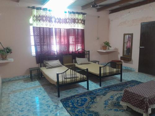 Habitación con 2 camas, mesa y ventana en Giriraj Darshan, en Govardhan