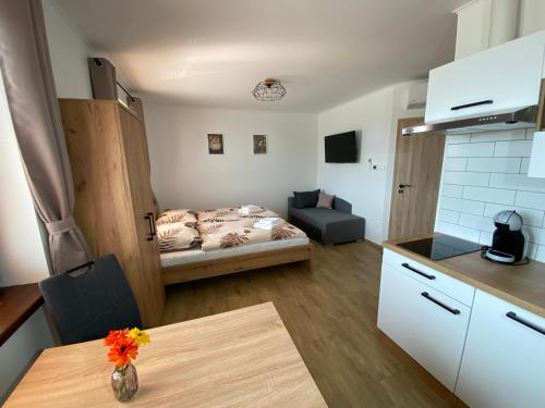 eine Küche und ein Wohnzimmer mit einem Tisch und einem Bett in der Unterkunft Apartmán Nezábudka in Nesvady