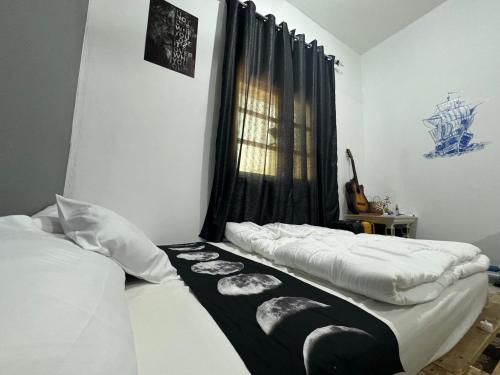 a bedroom with two beds and a window with a guitar at Shan Studio Apartment in Hatta