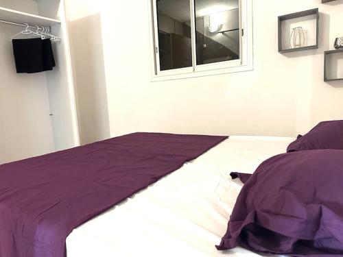 - un lit avec une couette violette et une fenêtre dans l'établissement chambre pour voyageur, à Bouéni