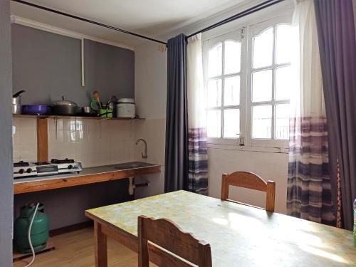 een keuken met een tafel en een raam en een tafel en stoelen bij Chez Jeanne Chambre d'Hôte in Antananarivo
