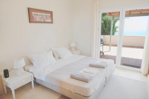 a white bedroom with a large bed and a balcony at Skyline Parorama in Mathía