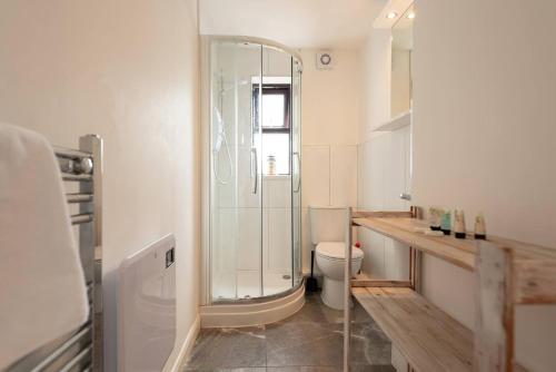 uma casa de banho com um WC e uma cabina de duche em vidro. em Pass the Keys The White House Holiday Cottage em Highley