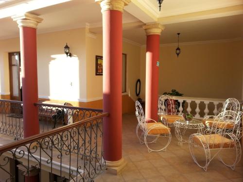 Villa Oropeza Hostel في سوكر: لوبي فيه اعمدة حمراء وطاولات وكراسي
