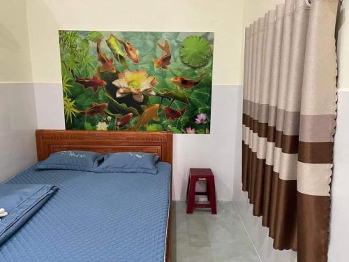 Un dormitorio con una cama azul y una pintura en la pared en Nhà trọ Hương Nguyên, en Dồng Xoài