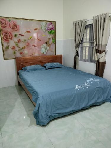 a bed with a blue comforter in a bedroom at Nhà trọ Hương Nguyên in Dồng Xoài
