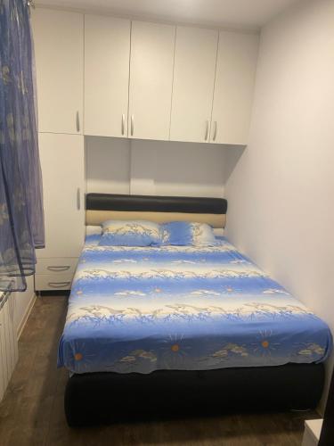クラグイェヴァツにあるMarta Apartmentのベッドルーム1室(青いシーツと白いキャビネット付きのベッド1台付)