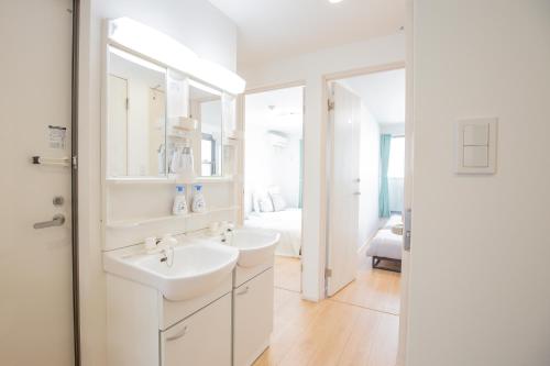 a white bathroom with two sinks and a bedroom at Comfort Walk to Takadanobaba Sta. - 3LDK SoYi / Dual Bathrooms & Washrooms for Families & Groups in Tokyo