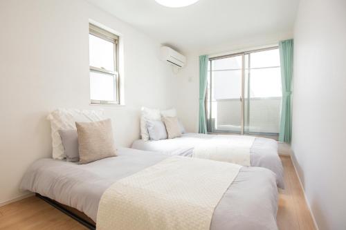 two beds in a room with two windows at Comfort Walk to Takadanobaba Sta. - 3LDK SoYi / Dual Bathrooms & Washrooms for Families & Groups in Tokyo