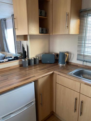 a kitchen with a wooden counter top with a sink at Coastal caravan retreat in Brightlingsea
