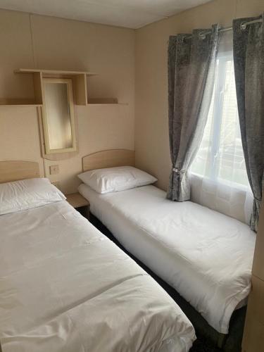 two beds in a small room with a window at Coastal caravan retreat in Brightlingsea