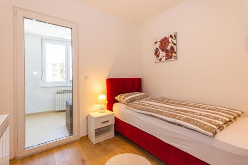 a small bedroom with a bed and a mirror at Apartman Krželj B2 in Livno