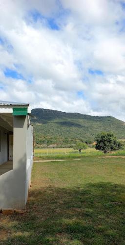 a building in a field with a mountain in the background at The Wild Olive Sanctuary Accommodation in Paterson
