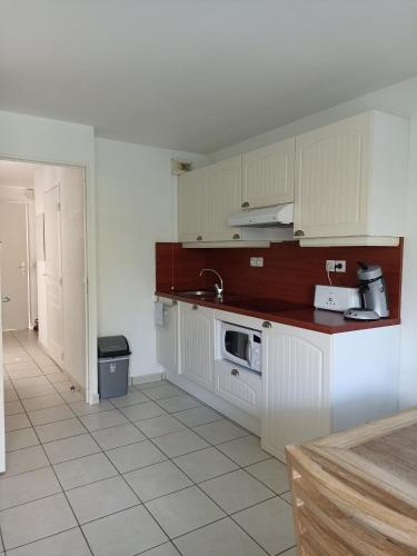 une cuisine avec des armoires blanches et un évier dans l'établissement Location appartement meublé bord de mer, à Fouesnant