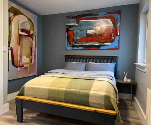 a bedroom with a bed with two paintings on the wall at “ The Art House 4” Galway, Woodquay in Galway