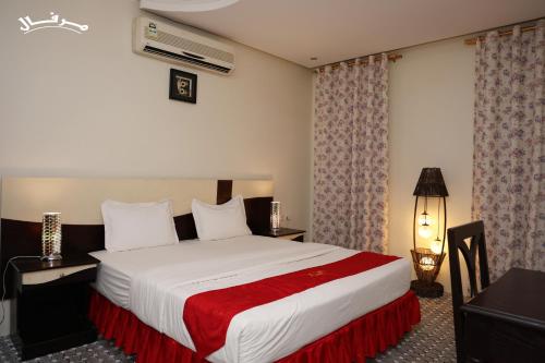 1 dormitorio con 1 cama grande con manta roja en Merfal Hotel Apartments Al Taawan مرفال التعاون, en Riad
