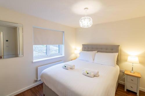 Un dormitorio con una cama blanca con dos animales de peluche. en Pass the Keys Modern comfortable House, en Elswick