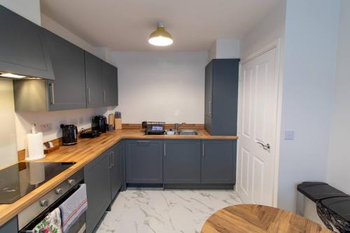 a kitchen with blue cabinets and a wooden counter top at Pass the Keys Modern comfortable House in Elswick