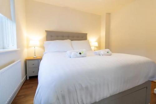 a bedroom with a white bed with two stuffed animals on it at Pass the Keys Modern comfortable House in Elswick