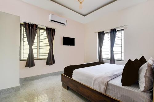 a bedroom with white walls and windows and a bed at OYO ALYSAN STAY in Bhubaneshwar