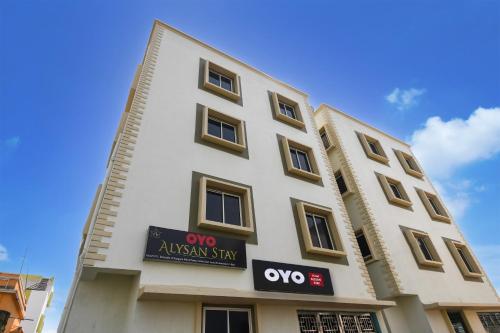 a tall white building with aiya stay sign on it at OYO ALYSAN STAY in Bhubaneshwar