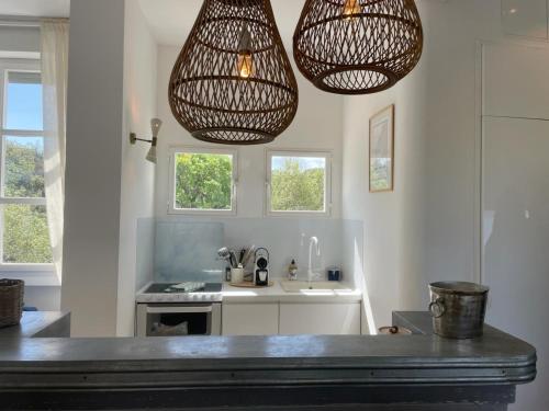 - une cuisine avec deux lampes suspendues et un évier dans l'établissement Appartement standing, vue Golfe avec parking gratuit, à Saint-Tropez