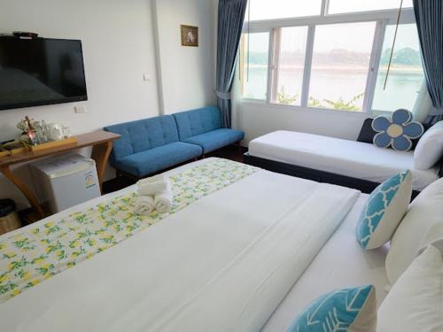 a hotel room with two beds and a flat screen tv at โมเมนต์ แอ๊ท ริมโขง in Chiang Khan