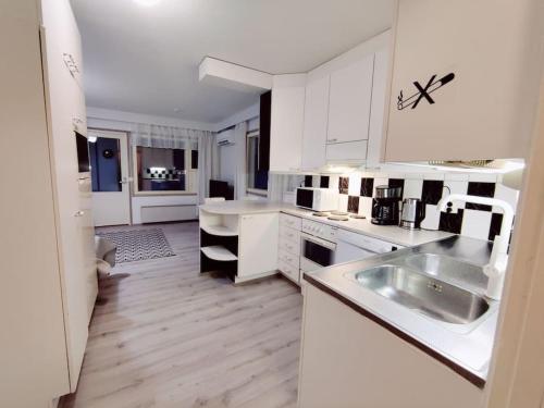 a white kitchen with white cabinets and a sink at Yksiö saunalla in Kuusamo