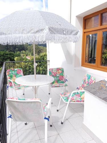 a table and chairs with an umbrella on a balcony at Casa Calvo in Viveiro